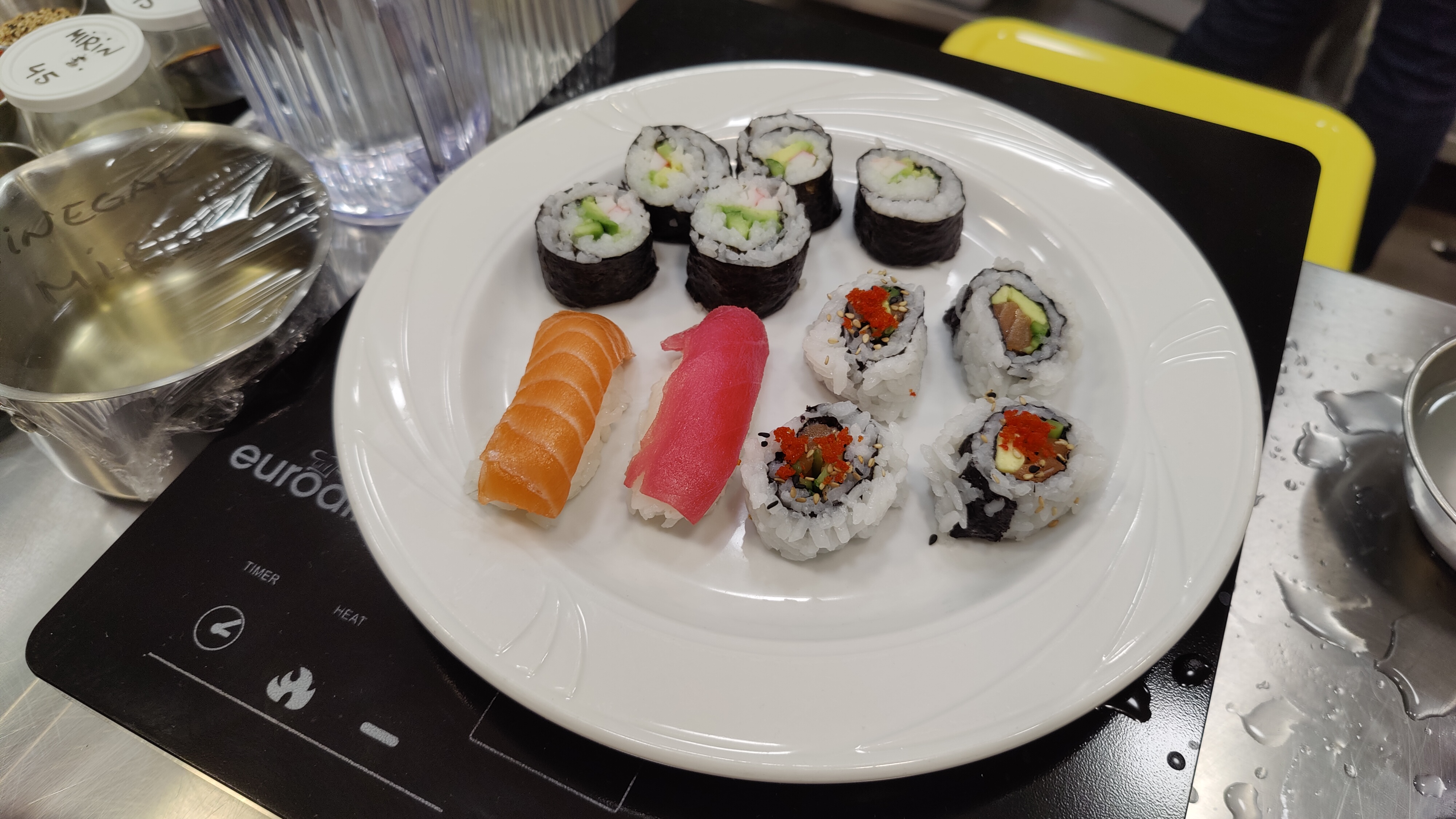 Crab maki, reverse-wrapped salmon maki, and salmon and tuna nigiri sushi sit on a plate.